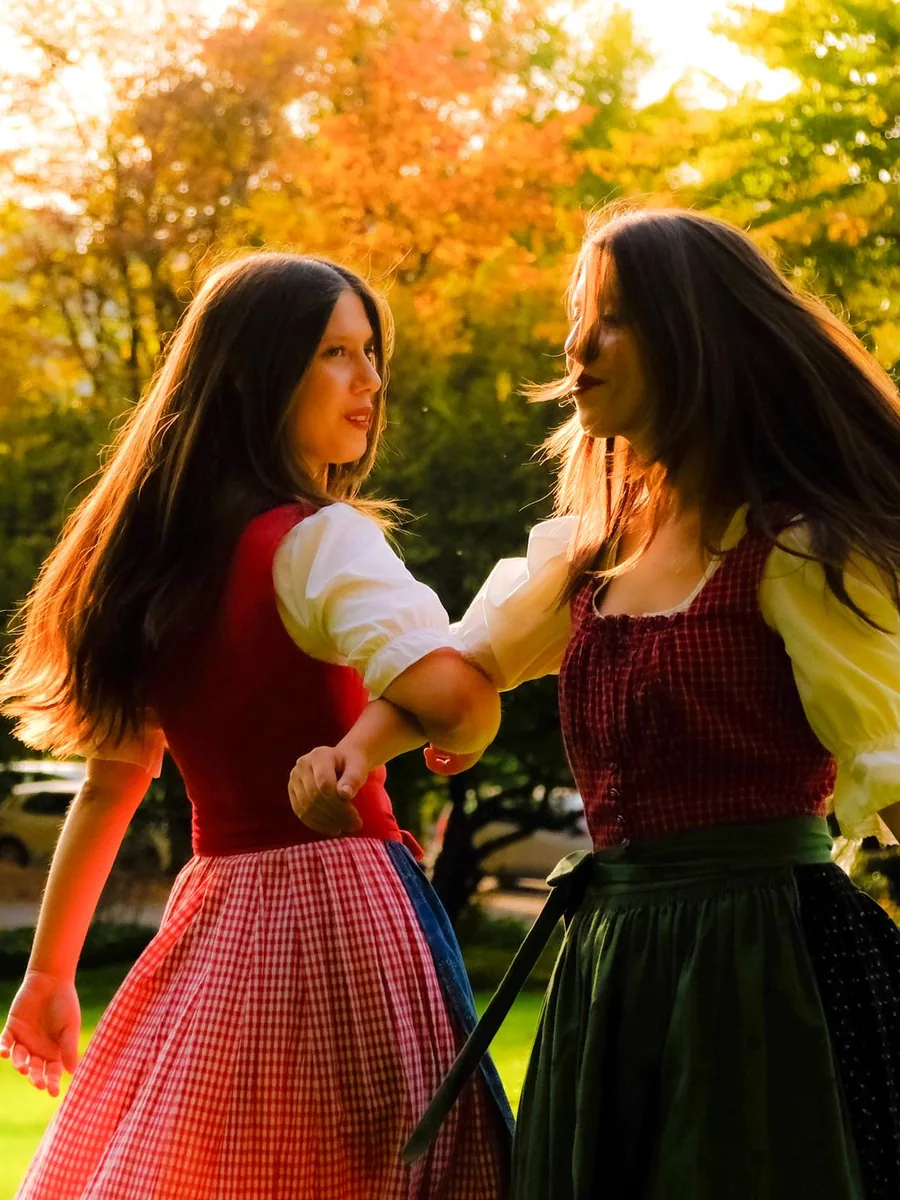Two women in embroidered folk dress dancing outdoors