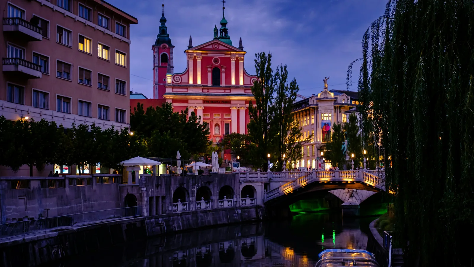 The Triple Bridge and a riverside church in Ljubljana's old town at night